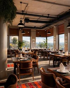 a restaurant with tables and chairs and large windows at Hotel Protino in Fushë-Prezë