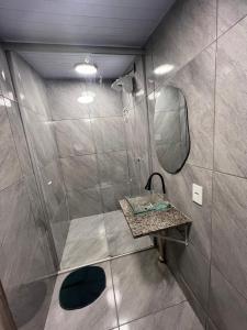 a bathroom with a shower with a sink and a mirror at Refúgio 4 in Belo Horizonte