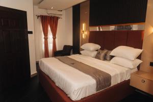 a bedroom with a large bed with white sheets and pillows at Muster Point Hotel & Suites in Port Harcourt