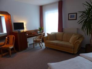 ein Wohnzimmer mit einer Couch und einem Schreibtisch mit einem Computer in der Unterkunft Hotel Dorotheenhof in Cottbus