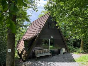 a small black cabin with a bench in front of it at ArdennenVakantieBungalow in Durbuy