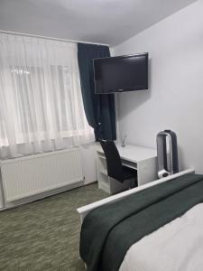 ein Schlafzimmer mit Bett und Schreibtisch mit Fernseher in der Unterkunft VivaVero in Baia Mare