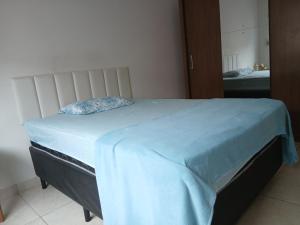 a bedroom with a bed with a blue blanket on it at Quarto Rustico em Alfenas in Alfenas