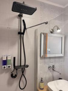 a shower head in a bathroom with a mirror at Contact Apartman in Bardejov +29 photos