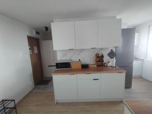 a kitchen with white cabinets and a wooden counter top at Apartament Na Głucho in Nysa