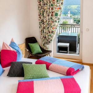 a bedroom with a bed with colorful pillows and a window at "schön-urlauben" in Gröbming