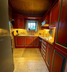 a kitchen with red cabinets and a window at Cabin in Tuddal in Hjartdal +25 photos