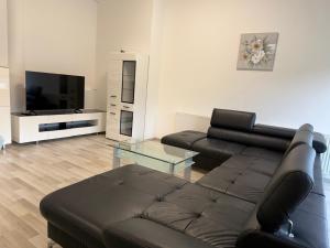 a living room with a black leather couch and a tv at Komfortresidenz Harmonie in Weiz