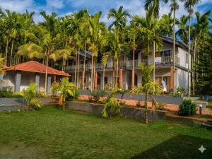a building with palm trees in front of it at Sree Durga Veerabhoomi Resort in Kushālnagar