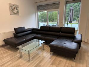 a living room with a black leather couch and a glass table at Komfortresidenz Harmonie in Weiz