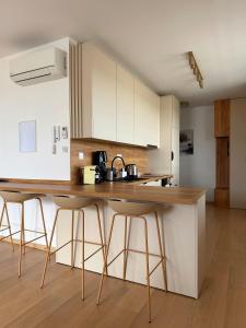 a kitchen with white cabinets and bar stools at Modra Sunny Apartment in Modra