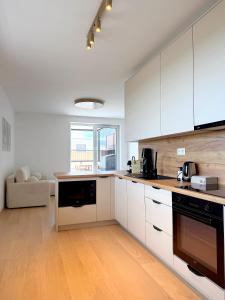 a kitchen with white cabinets and a couch in a room at Modra Sunny Apartment in Modra +14 photos