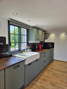 a kitchen with a white sink and a window at Le logis de la mésanges Bleue in Gignac
