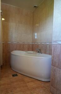 a white tub in a bathroom with a tiled wall at Konačište Compass in Kraljevo