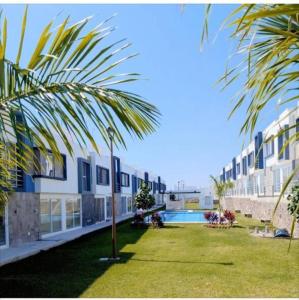 a palm tree in front of a building with a pool at Residencial Granate Xochitepec Morelos in Atlacholoaya