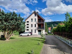a white house with a car parked in front of it at Apartament Parkowa 8 in Myślenice