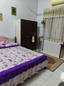 a bedroom with a bed with purple sheets and a cabinet at Homestay Rumah Inap ABC Semi-D in Pasir Mas