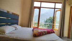 a bedroom with a bed with a large window at Hotel Aditya in Dharāsu