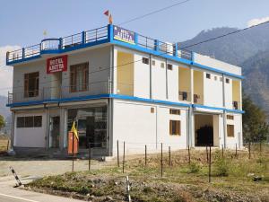 a white and yellow building with a balcony at Hotel Aditya in Dharāsu