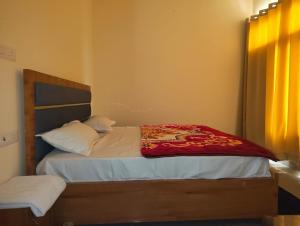 a bedroom with a bed with a red blanket on it at Hotel Aditya in Dharāsu
