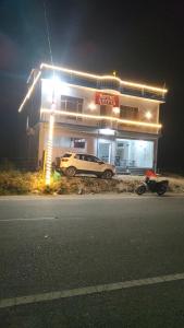 a car parked in front of a gas station at night at Hotel Aditya in Dharāsu