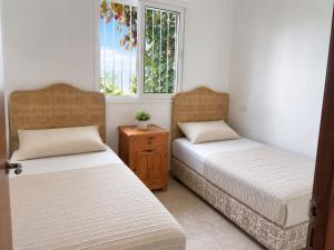 two beds in a room with two windows at Beachside Garden Apartment in Marina Smir in Marina Smir