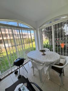 a white table and chairs in a room with windows at Beachside Garden Apartment in Marina Smir in Marina Smir +6 photos