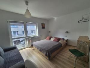 a bedroom with a bed and a couch and a window at Noclegi u Loni- pokoje studio w zacisznym centrum nad morzem z parkingiem in Pobierowo