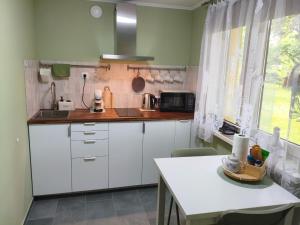 a kitchen with white cabinets and a white table at Lerihouse in Saulkrasti