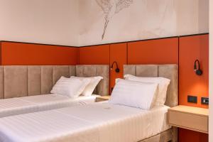 two beds in a room with orange walls at Golden Nina Hotel in Vlorë