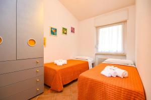 two beds in a room with orange sheets at Residence Kormorano Malcesine Apt 52 in Malcesine +22 photos