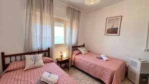 two beds in a room with a window at Todimer Acera del Mar in Torrenueva