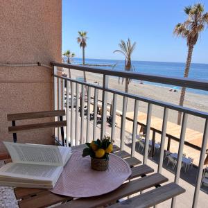 a table with a book on a balcony with the beach at Todimer Acera del Mar in Torrenueva