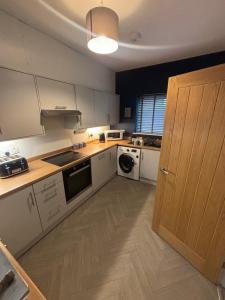 a kitchen with white cabinets and a wooden door at Nirvana house in Deepcar