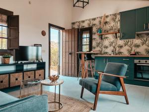 a kitchen with green cabinets and a chair and a table at Finca Flamenco Holiday Suites Adults Only in Pizarra