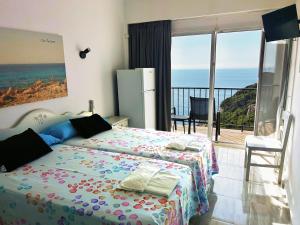 a bedroom with a bed and a view of the ocean at Hotel Rocamar in Cala Figuera +127 photos