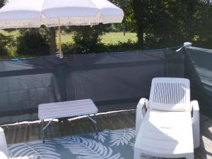 two white chairs and an umbrella on a patio at Gite "home" - piscine in Juvigny-le-Tertre +10 photos
