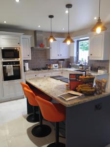 a kitchen with a counter with orange bar stools at Dunfolan House in Dundrum