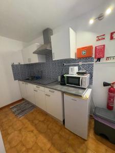 Eine Küche mit weißen Schränken und einer Mikrowelle auf der Arbeitsplatte. in der Unterkunft House Calhambeque in Meimoa + 13 Fotos