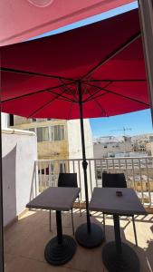 a red umbrella and two tables on a balcony at Elba Apartment in Msida