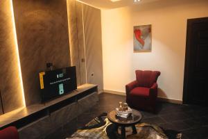 a living room with a tv and a red chair at Muster Point Hotel & Suites in Port Harcourt
