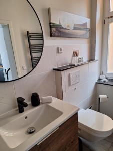 a bathroom with a sink and a toilet and a mirror at Ferienwohnung III in Eisenhüttenstadt