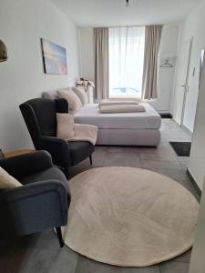 a bedroom with a bed and a couch and chairs at Ferienwohnung III in Eisenhüttenstadt