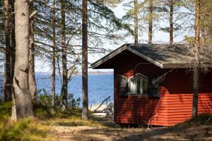 a red cabin in the woods with a view of the water at Gnista Glamping in Fäboda