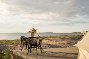 a table and chairs on the beach next to a tent at Gnista Glamping in Fäboda