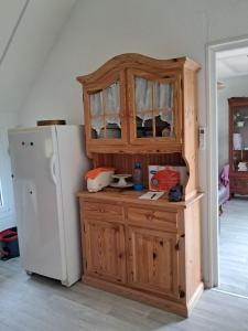 a kitchen with a wooden cabinet next to a refrigerator at La Châtelaine in Lombez