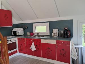 a kitchen with red cabinets and a sink at La Châtelaine in Lombez