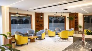a waiting room with yellow chairs and tables at Asfar Hotel Apartments أسفار للشقق الفندقية in Muscat