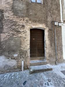 kamienny budynek z drewnianymi drzwiami i schodami w obiekcie Appartement Corte w mieście Corte