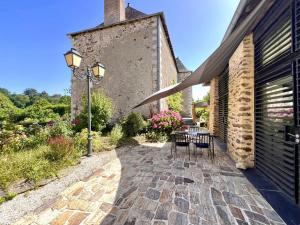 a patio with a table and chairs next to a building at Le Petit Vigneau in Ménil